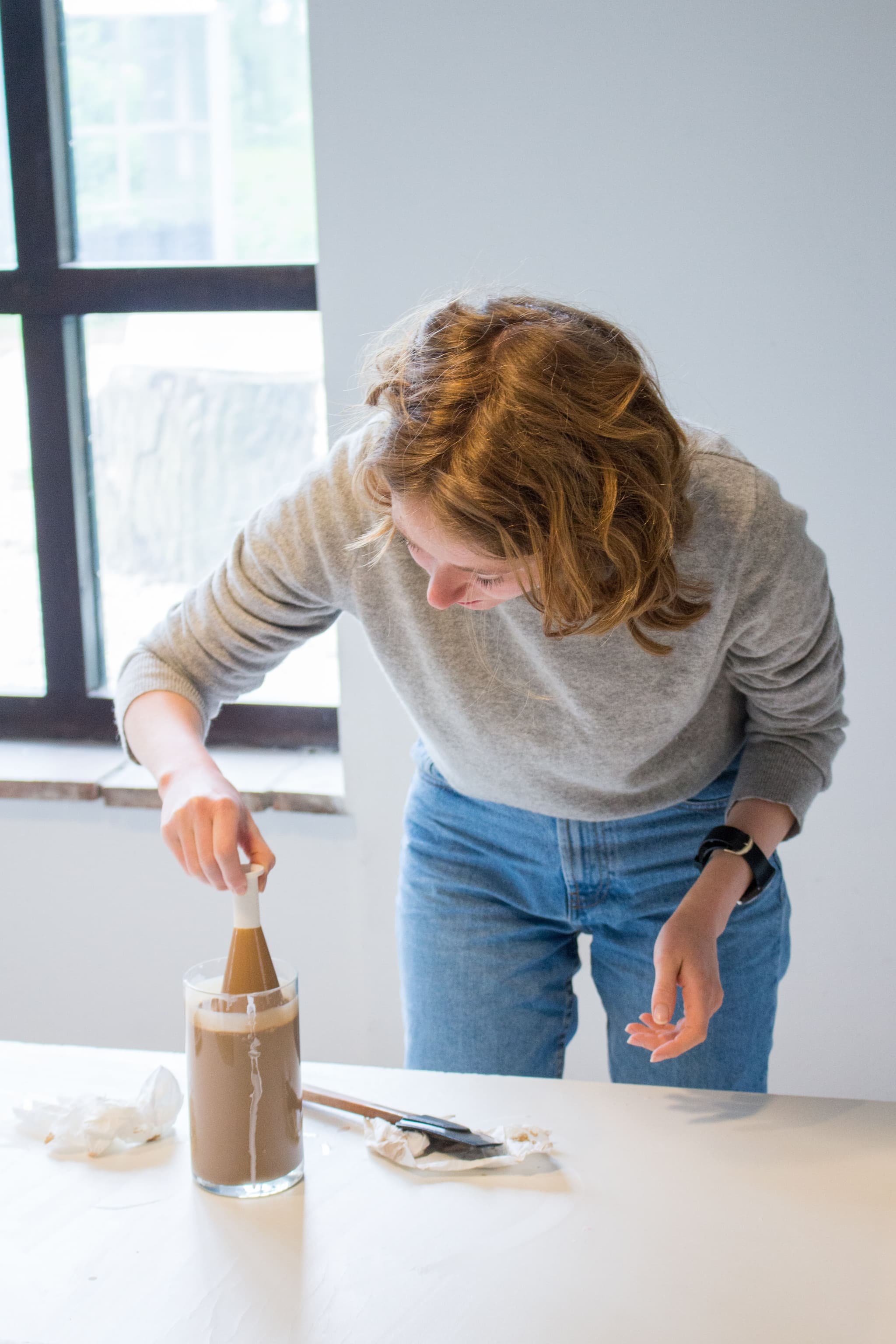 Carla applying a first layer of terra sigillata by dipping one white fired sample